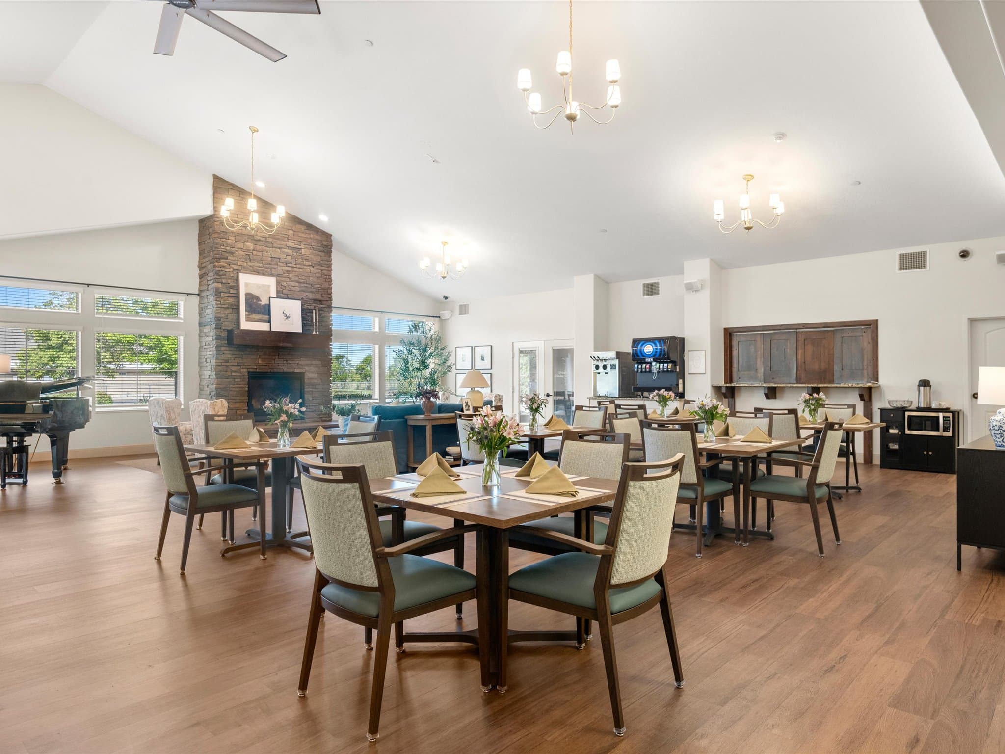 Assisted living dining room with tables set near the fireplace and piano