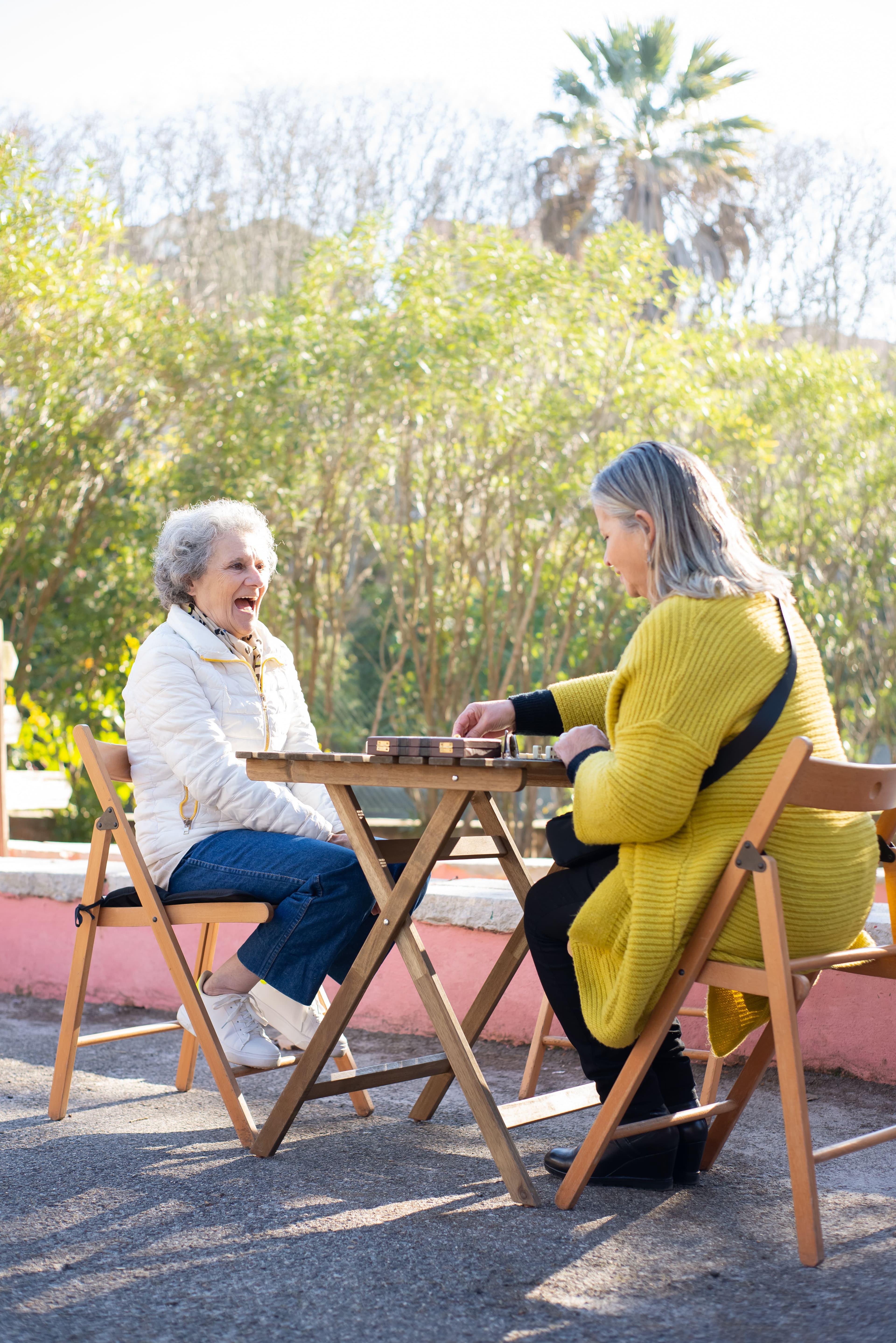 Two women laughing together at an outdoor table